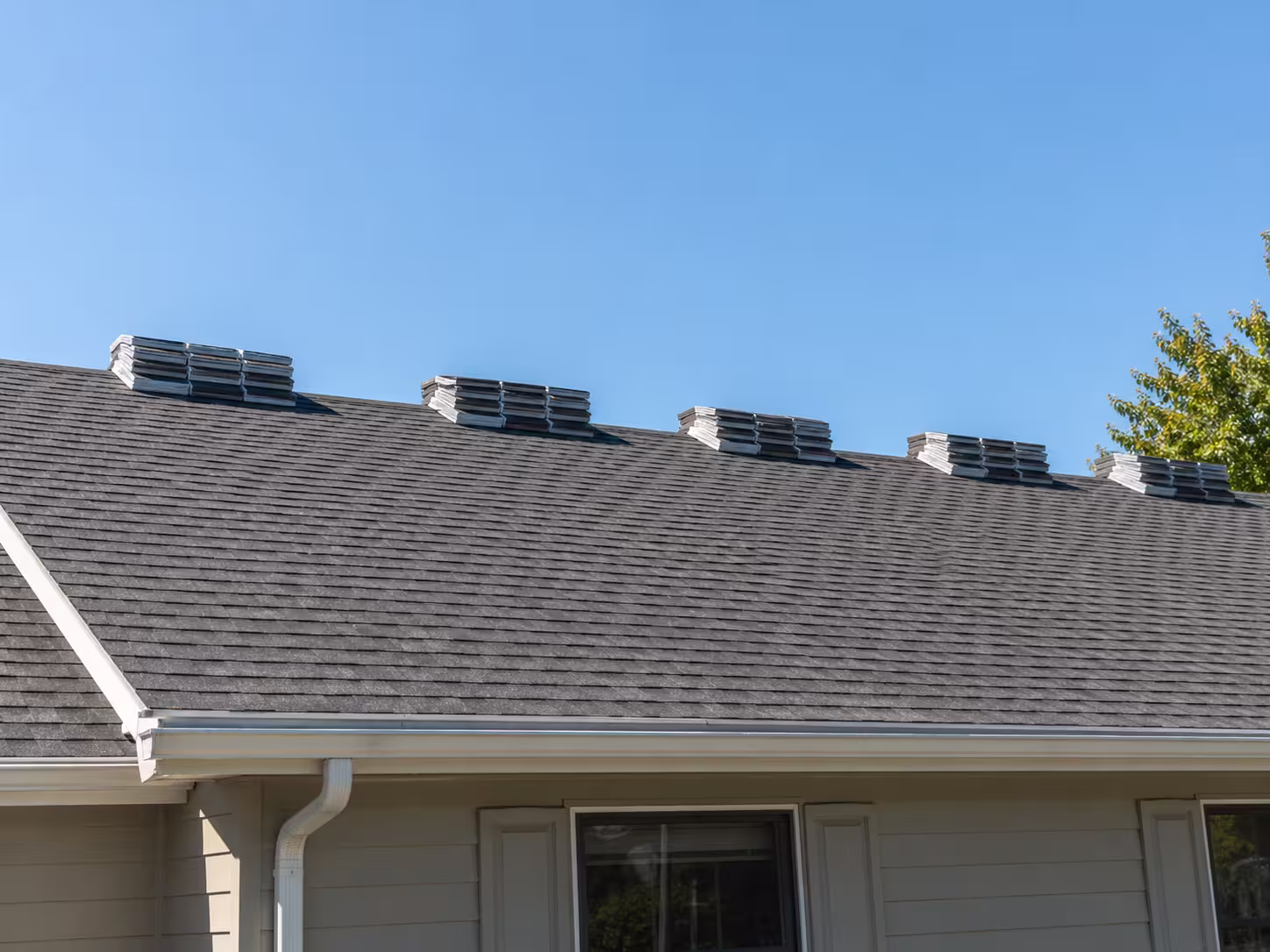 Architectural shingle bundles staged on a residential roof deck with a measuring tape, ready for installation